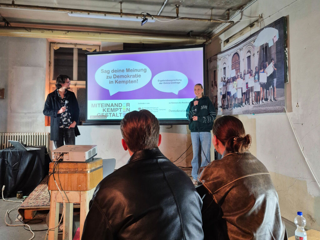 Ein Pärchen schaut gespannt auf die Bühne wo gerade sich die beiden Hosts des Abends vorstellen