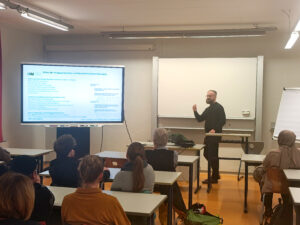 Nahostvortrag Vorne referiert Dr. Sascha Rupert-Karakas zum Nahostkonflikt. Viele Gäste hören Aufmerksam zu.