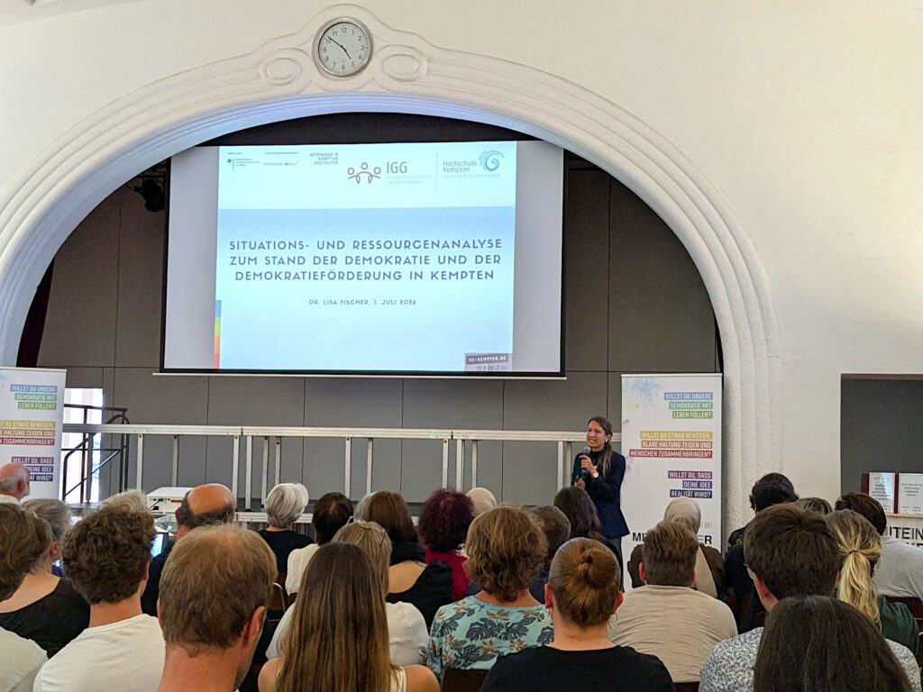 Dr Lisa Fischer stellt auf der Demokratiekonferenz die Situations- und Ressourcenanalyse vor.