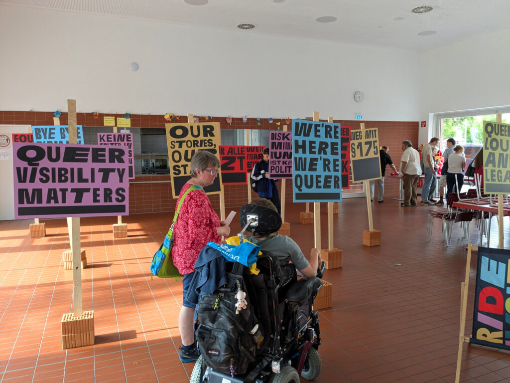 Zwei Personen im Schilderwald der Ausstellung Pride Revolt