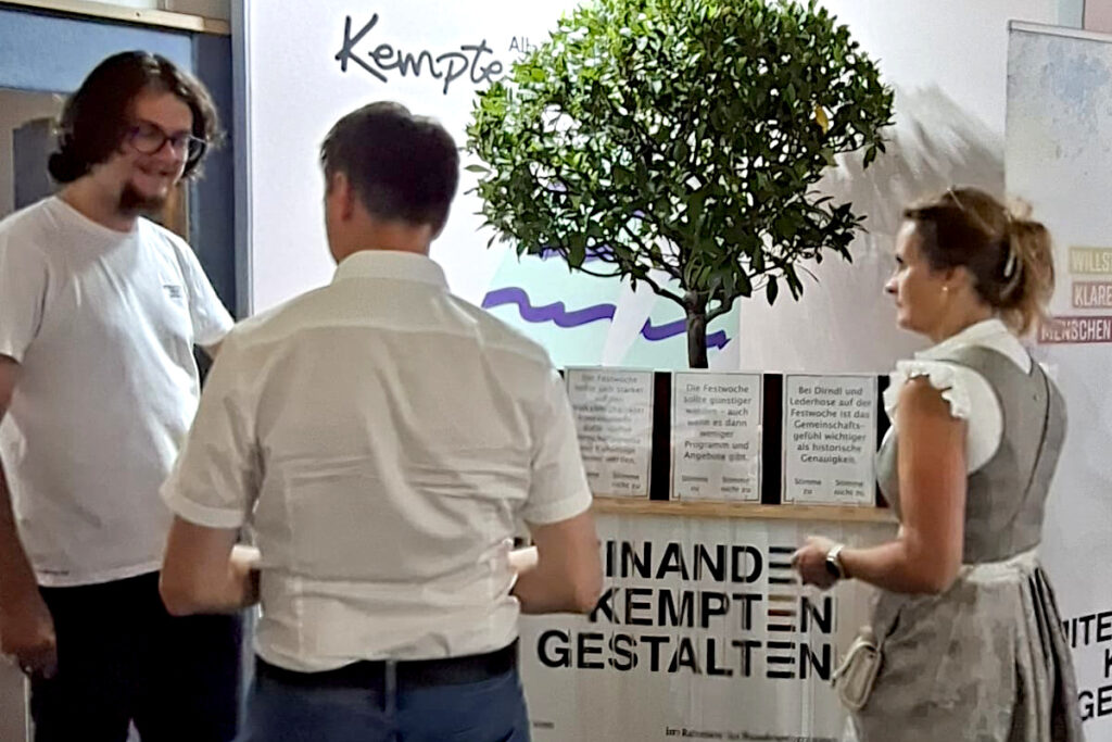 Besucher:innen diskutieren am Stand von „Demokratie leben!“ über Aussagen zur Allgäuer Festwoche und geben ihre Stimme am Abstimmungsspiel ab.